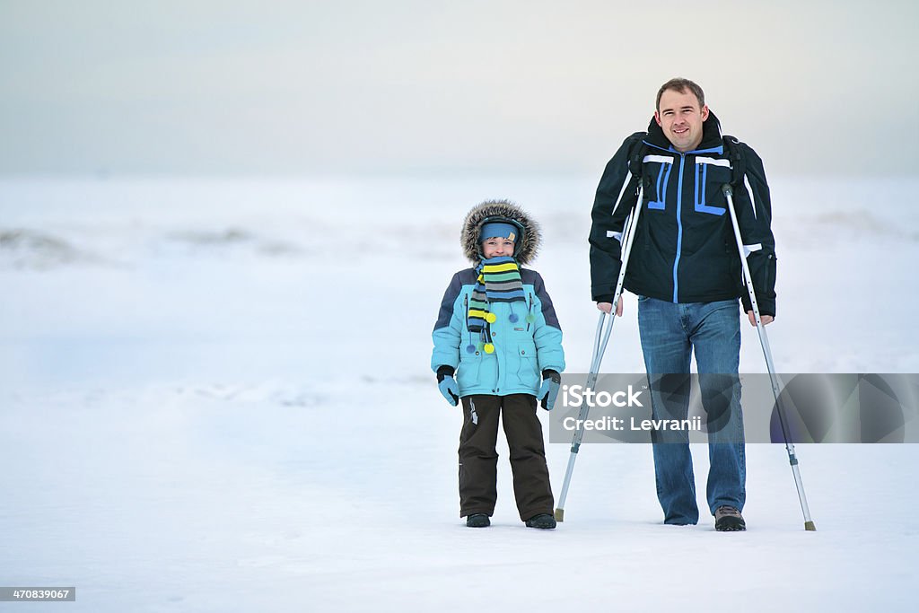 crutches hombre con su hijo y caminando al aire libre - Foto de stock de Adulto libre de derechos