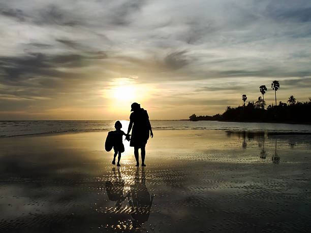 A silhueta da família Assistindo o nascer do sol na praia - foto de acervo
