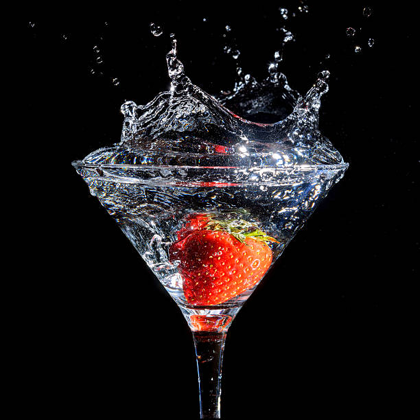 A close-up of a delicious and creamy strawberry smoothie in a glass, garnished with dried fruit and accompanied by a black straw. The smoothie is placed on a dark table against a soft neutral background, creating a minimalist and elegant composition. This image is perfect for content related to healthy drinks, fruit smoothies, Thai beverages, summer refreshments, and wellness-focused dining.