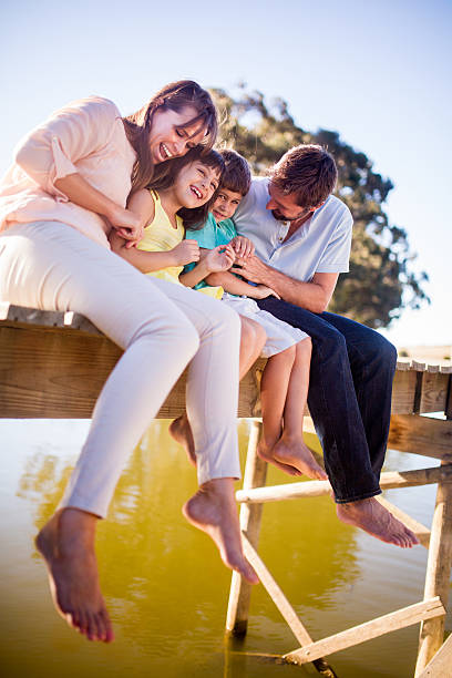 istock Parents tickling their laughing children while sitting on a jetty 470844124