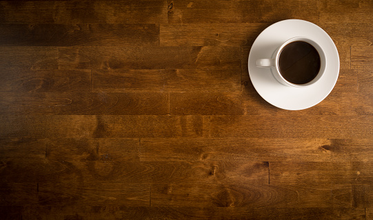 Coffee in white cup on a saucer on a wooden table