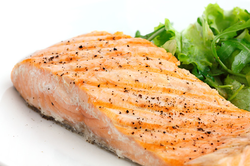 Grilled fillet of salmon on plate with green salad.