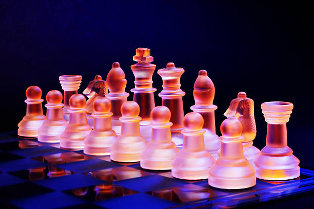glas schach auf der schachbrett-hell blau und orange licht - armed forces black yellow chess pawn stock-fotos und bilder