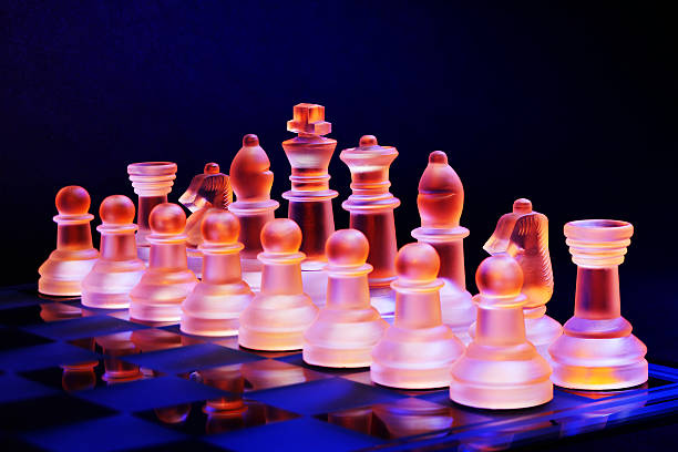 istock Glass chess on chessboard lit by blue and orange light 470857353