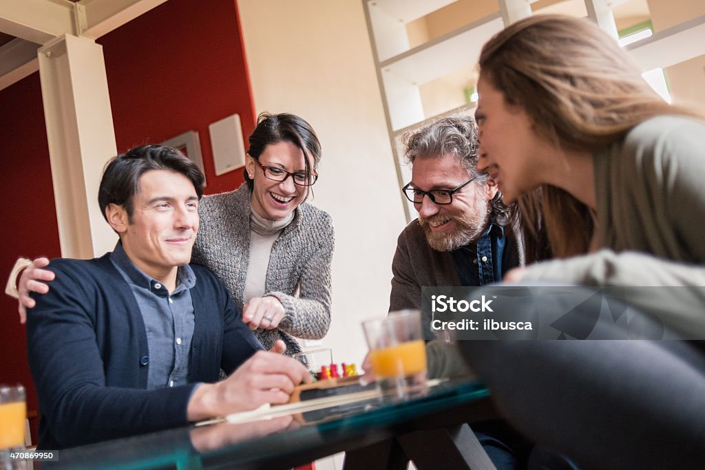 Friends playing cards and games, drinking in modern apartment 20-29 Years Stock Photo