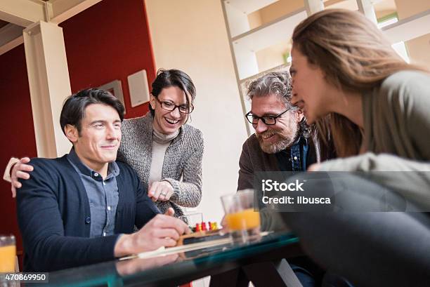 Friends Playing Cards And Games Drinking In Modern Apartment Stock Photo - Download Image Now