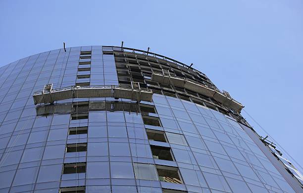 ガラス張りの工事中の建物の壁に吊り足場ます。 - steel construction site construction glass ストックフォトと画像