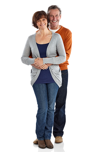 Full length portrait of happy mature man embracing his wife from behind wile standing on white background