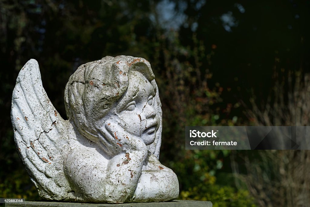 putto child angel statue of ceramic with flaking white paint putto or child angel statue of ceramic with flaking white paint on an old cemetery park, copy space Angel Stock Photo
