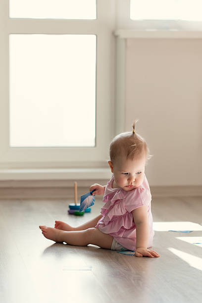 istock Little girl playing with pyramid on floor 470883770