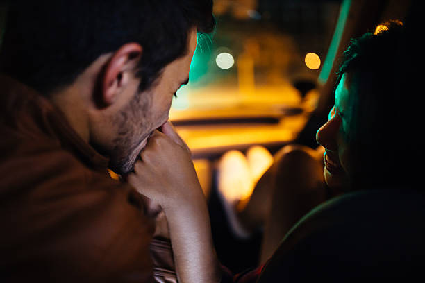Sweet guy kissing his girlfriend's hand to say goodnight in a car