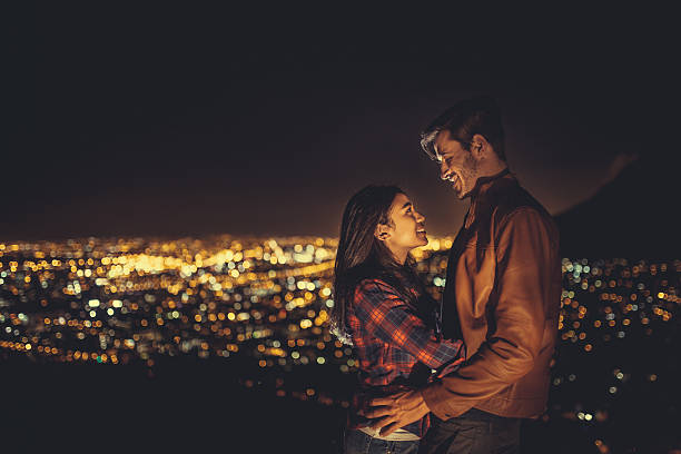 istock Young couple hugging at night with the city behind 470892542