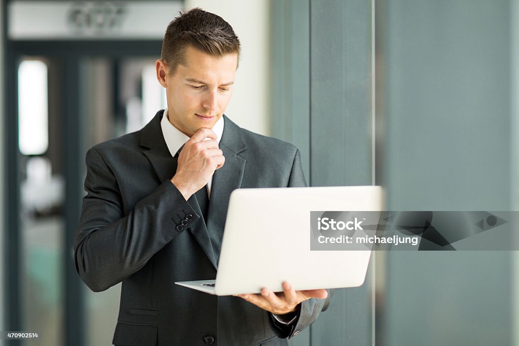 businessman reading email on his laptop handsome businessman reading email on his laptop Businessman Stock Photo