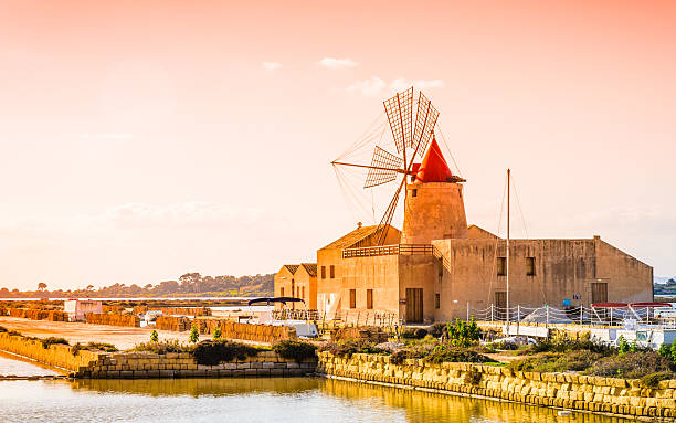 Sicily, sea salt production, Trapani,Italy.Nature reserve in the Province of Trapani and Paceco, Sicily,Italy.Old windwill  and salt pans at sunset.