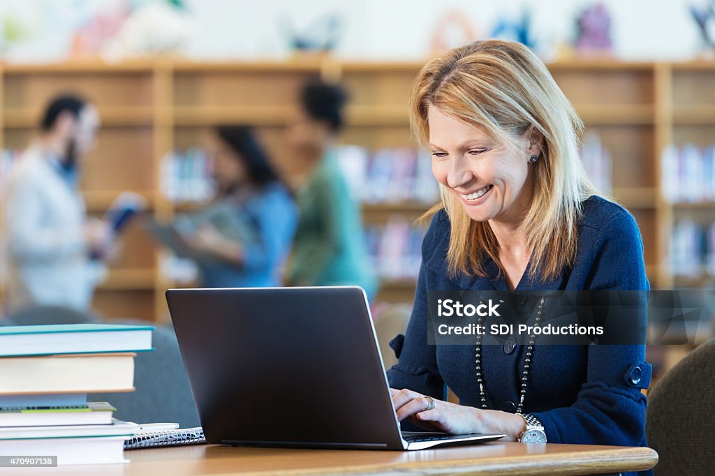 Mature adult woman studying for college class in library Production Tool Ref #12 Computer Stock Photo