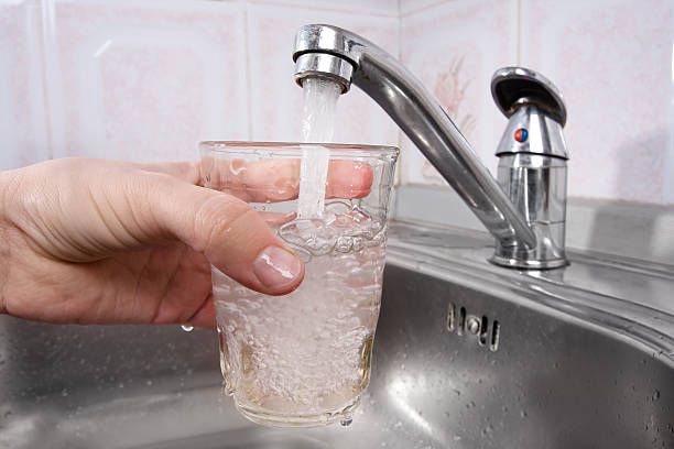 istock hand pours water into a glass from  faucet 470911940
