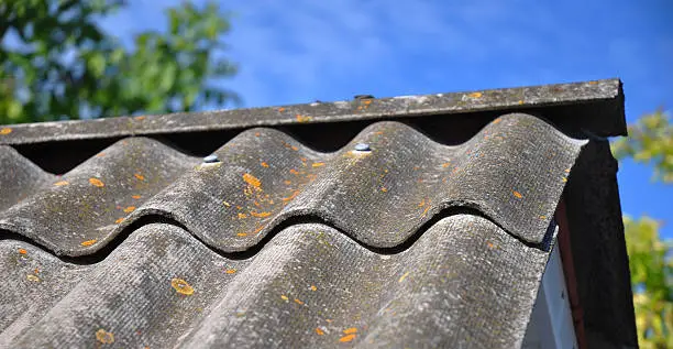 Photo of Blue sky over the dangerous asbestos old roof tiles