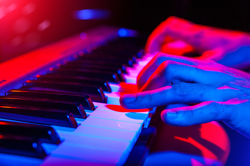 hands of musician playing keyboard in concert with shallow depth of field