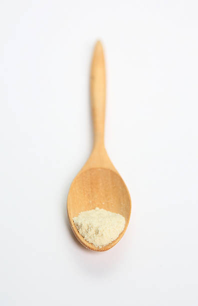 istock Powdered milk in wooden spoon over white background 470913592