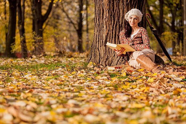 istock Young woman reading in the autumn forest 470914015
