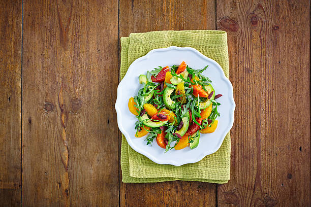 Fresh Moroccan salad Directly above shot of fresh avacado orange rocket and olive salad served on a plate on wooden counter arugula photos stock pictures, royalty-free photos & images