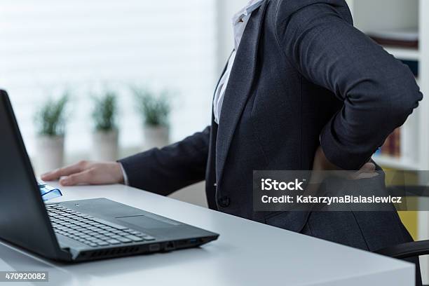 Woman Working On Laptop With Lower Back Pain Stock Photo - Download Image Now - Lower Back Pain, Office, Desk