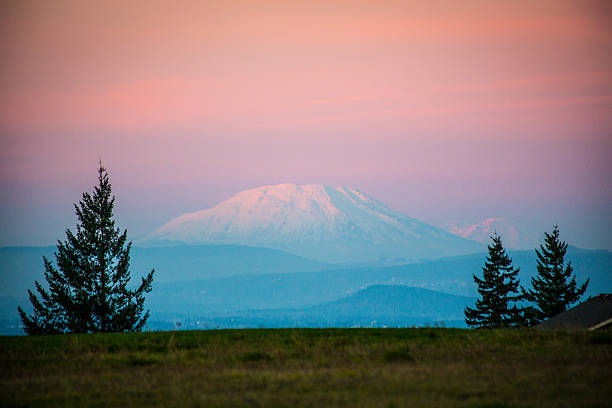 MT ST HELENS AT SUNSET The sun sets on Mt. St. Helens with Mt. Rainier in the distance behind it to the right. mount st helens stock pictures, royalty-free photos & images