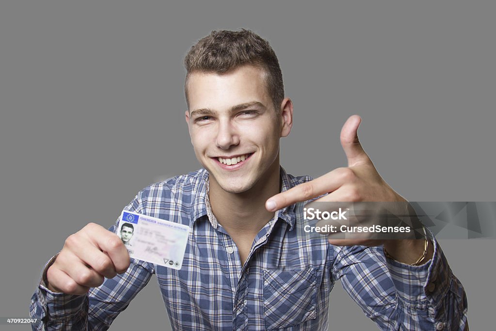 Young man showing off his driver license Young man just recieved his drivers license and is happy to drive his own car soon Driver's License Stock Photo