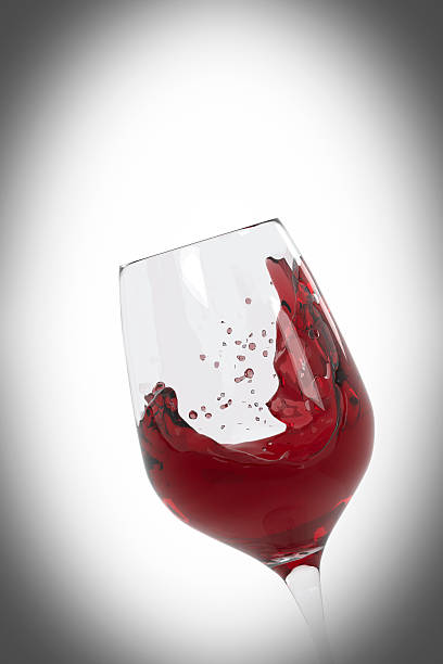 istock Red wine splashing in a wineglass (with vignette) 470923610