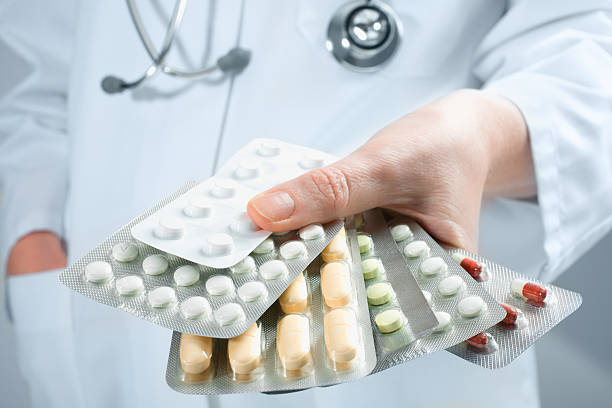 Doctor holding out several packs of medicine Hand of doctors holding many different pills self harm photos stock pictures, royalty-free photos & images