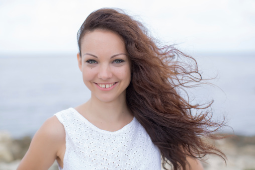 Stylish young woman posing against the background of the blue sea