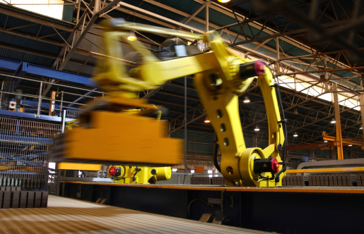 Automated robot picking up bricks on a conveyor in an automated brick making plant.