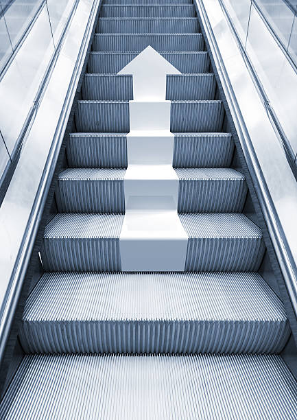 brillante metal escalera mecánica con flecha blanca moviendo hacia arriba - escalator steps staircase moving up fotografías e imágenes de stock