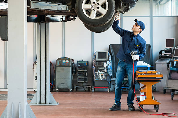 meccanico al lavoro nel suo garage - car examining mechanic auto mechanic foto e immagini stock