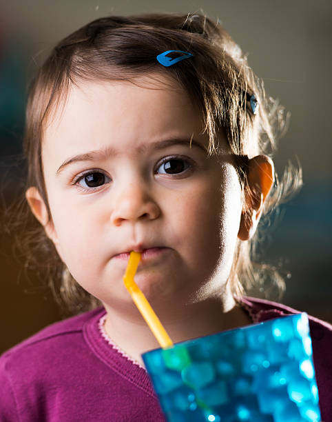 istock cute baby girl drinking with a straw 470934138