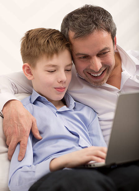 istock Happy dad and son with laptop at home 470934684