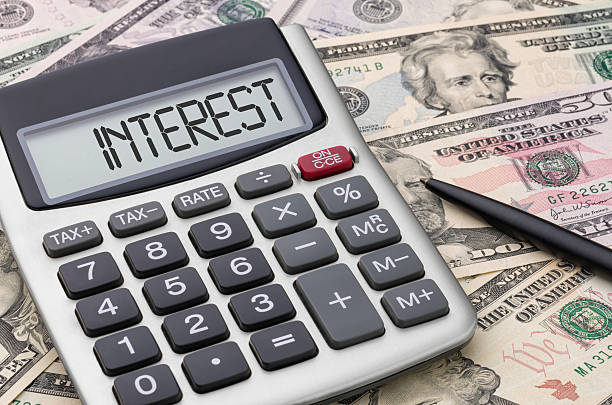 calculadora con dinero de interés - interest rate fotografías e imágenes de stock