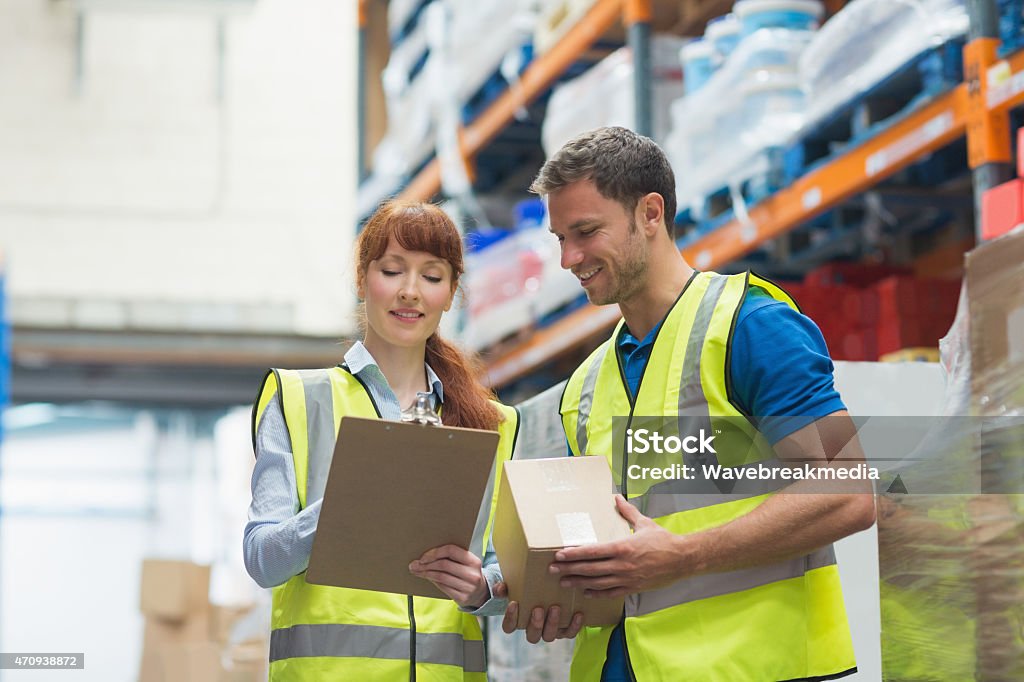 Smiling warehouse manager and delivery man Smiling warehouse manager and delivery man in warehouse Men Stock Photo