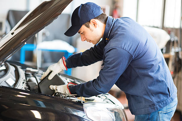Auto mechanic putting oil in a car engine
