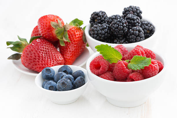 istock Fresh berries in bowls on a white wooden table 470943592
