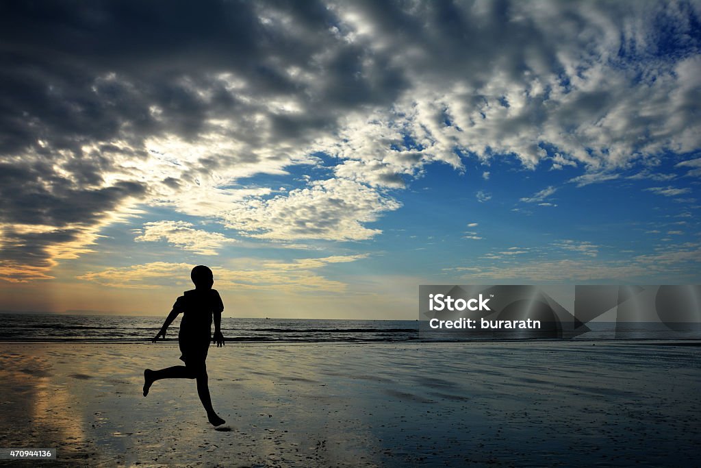 Silhouette kids running on the beach 2015 Stock Photo