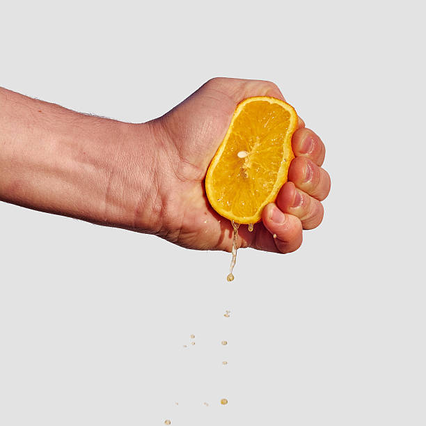 istock Man's hand squeezes the juice from the orange 470944184