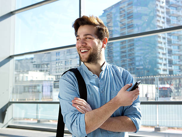 istock Cheerful young man standing at station with mobile phone 470944546