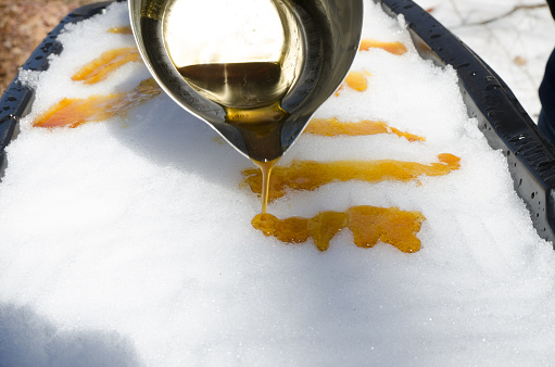 Pouring the maple syrup taffy from the cauldron over cold snow