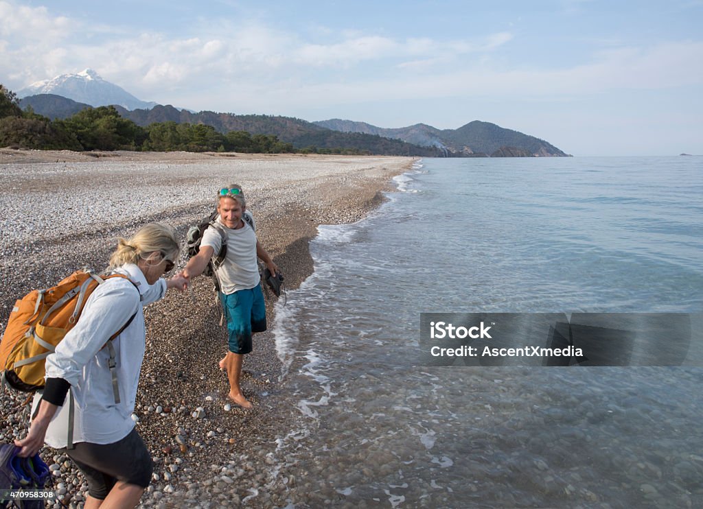 Man extends helping hand to woman on pebble beach Man extends helping hand to woman on pebble beach, seaside 2015 Stock Photo