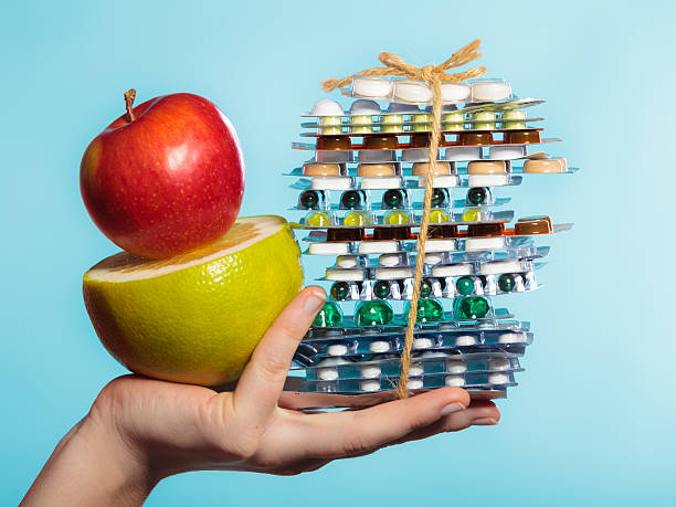 istock Human hand holding stack of pills and fruits on blue. 470958382