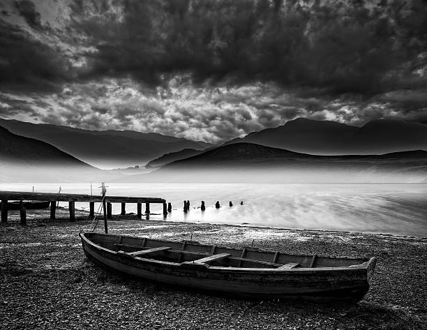 istock Old boat on lake with misty mountains landscape in storm 470965233