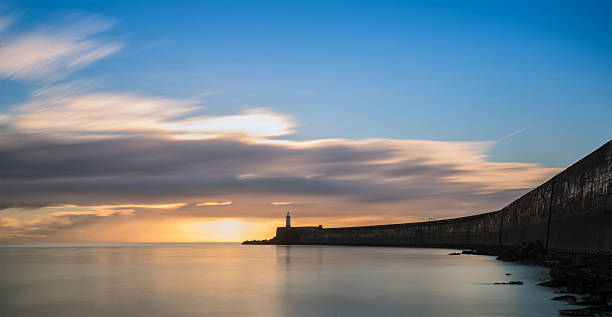 istock Beautiful vibrant sunrise sky over calm water ocean with lighthouse 470971473