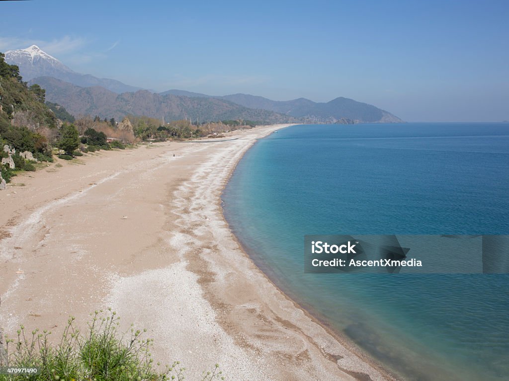 View down to pebble beach, hills and snowy mountains 2015 Stock Photo