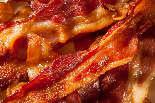 Crispy Organic Unhealthy Bacon Crispy Organic Unhealthy Bacon on a Background cooked bacon slice stock pictures, royalty-free photos & images